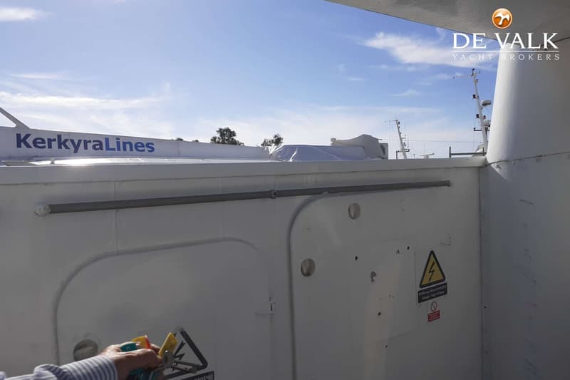 Een deel van een wit schip met de tekst "KerkyraLines" en een waarschuwingssticker voor hoogspanning.