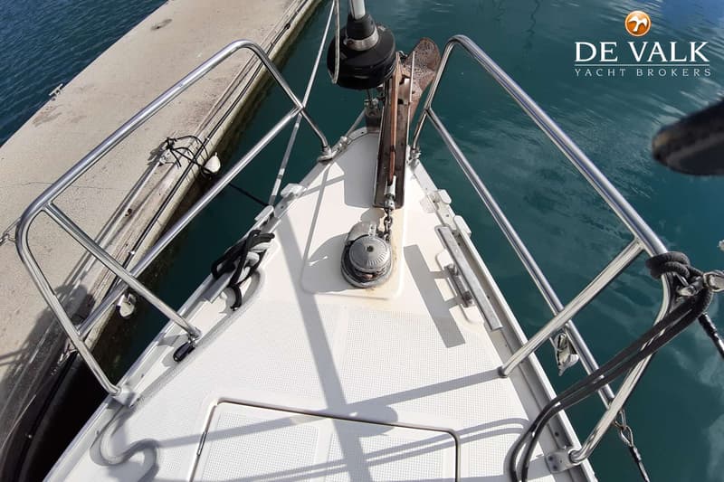 De foto toont de boeg van een boot met een anker, ankerlier en reling, liggend aan een kade. — Bavaria 46 Cruiser