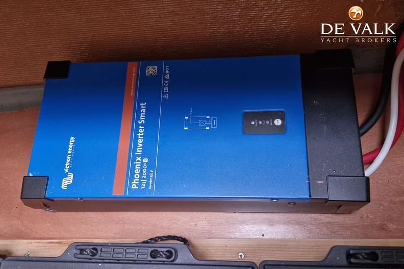Een blauwe Victron Energy Phoenix Inverter Smart 12|2000 met kabels en een schema is zichtbaar.