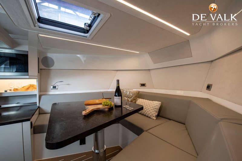 Een interieur van een boot met een tafel, banken, een fles wijn, glazen, brood, druiven en een magnetron. — Reborn 38 Cabin