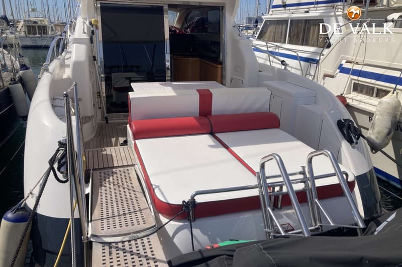 De achterkant van een witte boot met een rood-wit zonnedek en een zwemtrap, liggend in een haven. — Genesis Cielo 50