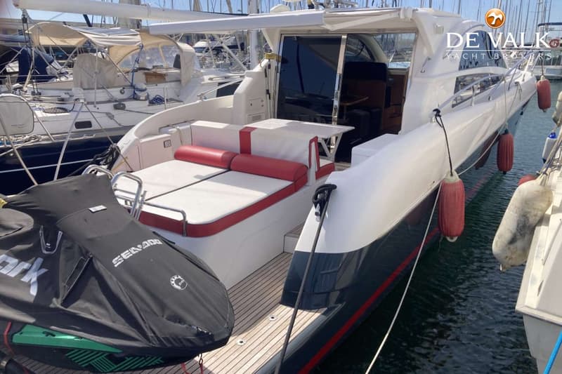 Een witte en donkerblauwe motorboot met een teakdek en rode kussens, met een jetski op het achterdek. — Genesis Cielo 50