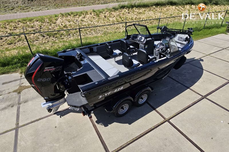 Een zwarte Crestliner boot met een Mercury Pro XS 200 buitenboordmotor staat op een trailer op een betonnen ondergrond.