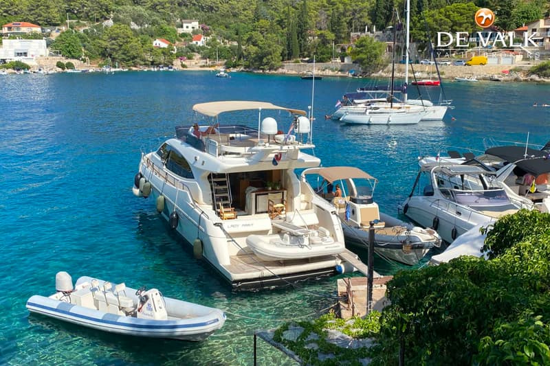 Een witte motorjacht met de naam "LADY MARIT" ligt aangemeerd in een baai met helderblauw water.