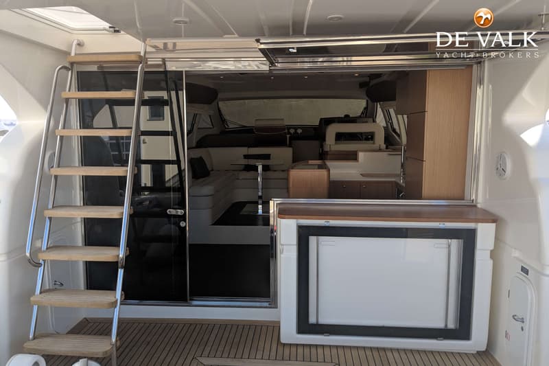 Een bootinterieur met een trap, schuifdeur, zitbanken, een tafel en een koelkast.