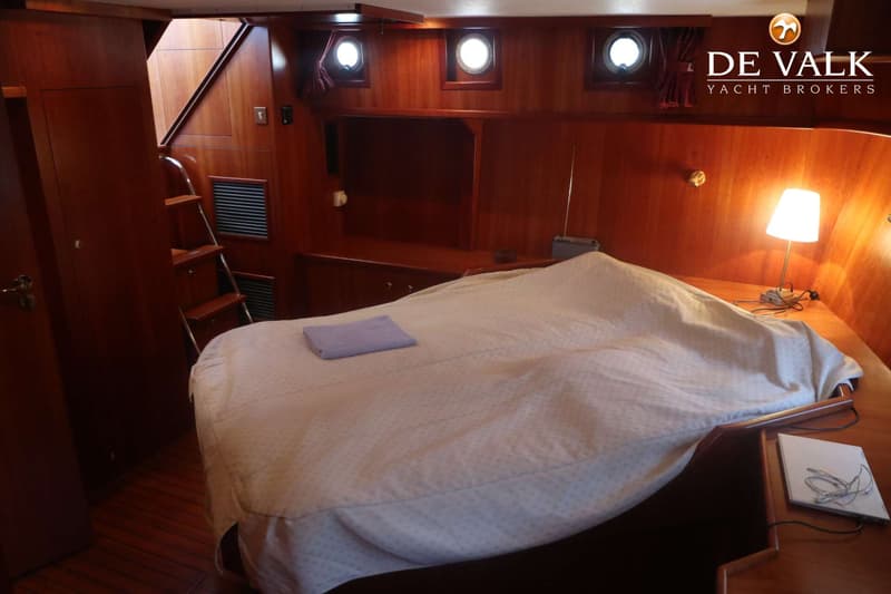 Een kajuit met een bed, houten lambrisering, patrijspoorten, een trap en een nachtkastje met een lamp. — Pilot 50