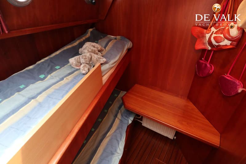 Een kajuit met een bed met gestreepte deken en een knuffel, en een houten plank met daaronder een radiator. — Pilot 50