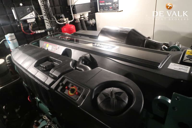 Een close-up van een scheepsmotor met een rood brandblusapparaat en een Onan Marine GenSet-paneel op de achtergrond.