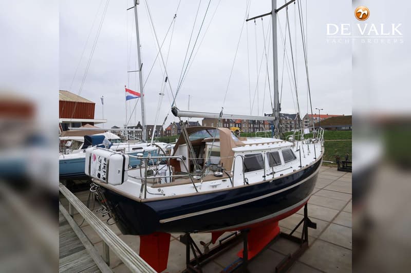 Een donkerblauwe zeilboot met witte opbouw en rode kiel staat op bokken op een betonnen ondergrond. — Endurance 38