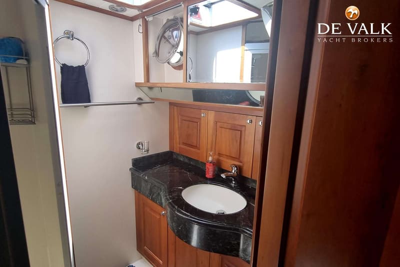 Een badkamer met een wastafel, een spiegelkast, een handdoekrek en houten kasten.