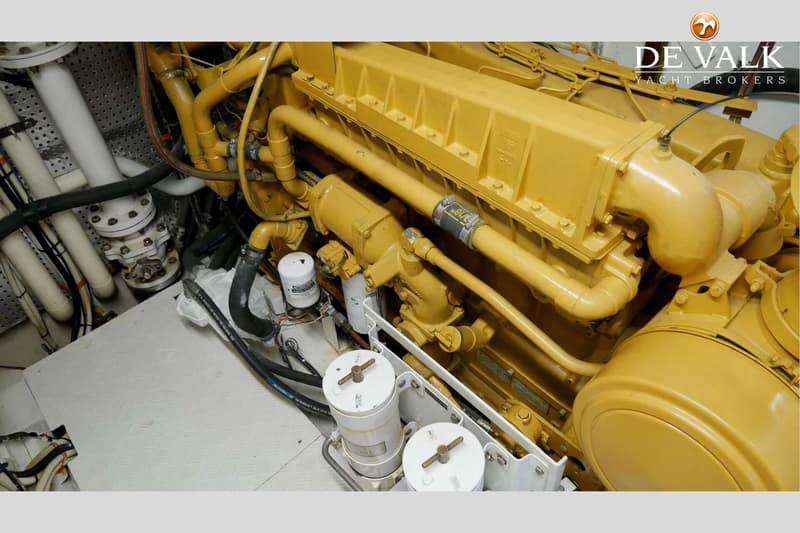 Een detailfoto van een gele scheepsmotor met diverse leidingen, filters en slangen.