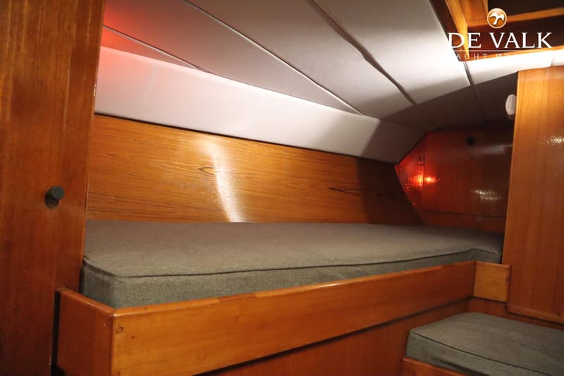 De foto toont een kajuit met houten wanden, een grijs matras en een rood verlichte hoek. — Dick Zaal 41