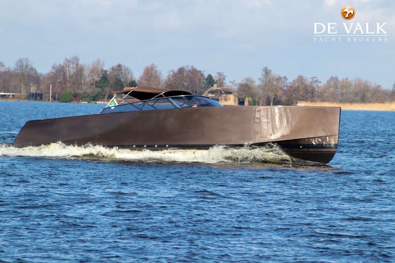 Een bruine motorboot vaart op blauw water, met bomen en rietkragen op de achtergrond. — VanDutch 40