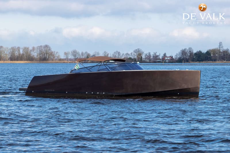 Een donkerbruine boot met een bruine bimini vaart op blauw water onder een lichtbewolkte hemel. — VanDutch 40