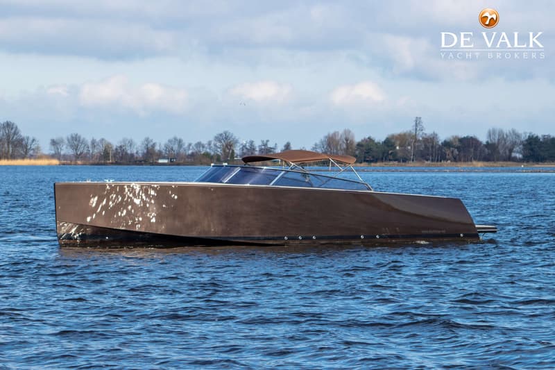 Een bruine motorboot met een bruine biminitop vaart op blauw water onder een lichtbewolkte hemel. — VanDutch 40