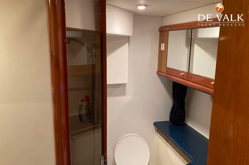 Een badkamer met een toilet, een douchecabine en een spiegelkast met houten omlijsting.