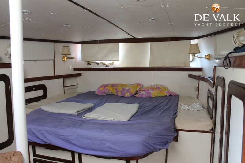 Een kajuit met een tweepersoonsbed met paars beddengoed en twee kussens, en een smalle slaapplek ernaast. — Suncoast 48