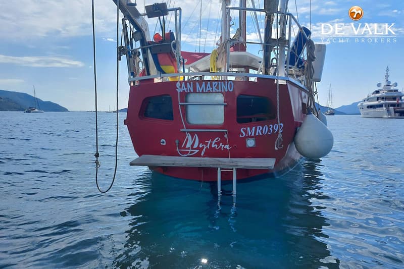 De achterkant van een rode boot met de naam "SAN MARINO" en "Mythra" is zichtbaar, met een zwemplateau en ladder.