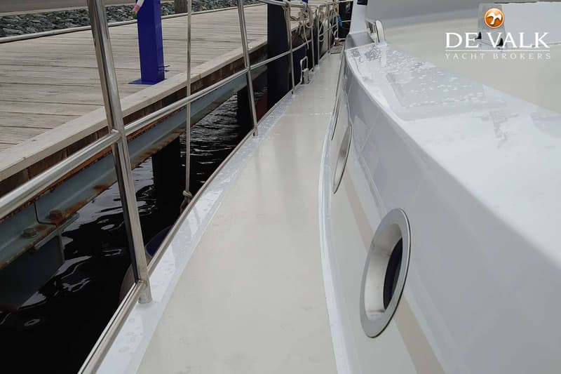 Een witte boot ligt afgemeerd aan een houten steiger, met een reling en patrijspoorten zichtbaar. — Pilot 44
