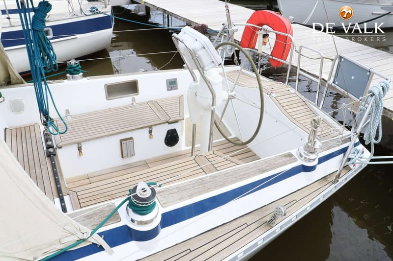 Een bovenaanzicht van de kuip van een zeilboot met een stuurwiel, teakdek en een reddingsboei. — Faurby 396