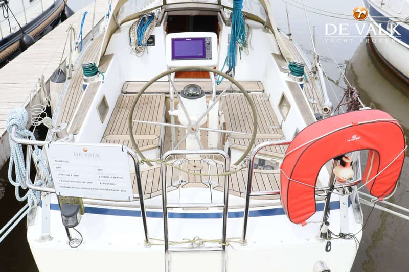 Een bovenaanzicht van de kuip van een zeilboot met een stuurwiel, navigatiescherm en een reddingsboei. — Faurby 396