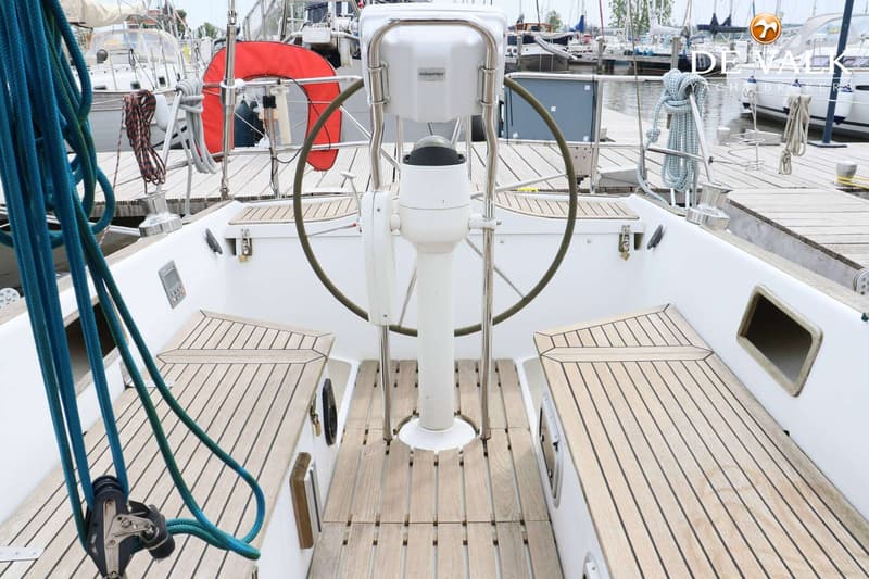 De kuip van een zeilboot met een stuurwiel, kompas, houten banken en een reddingsboei. — Faurby 396