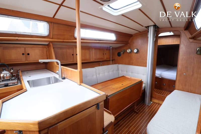De foto toont het interieur van een boot met een kombuis, zithoek en een doorgang naar een slaapcabine. — Faurby 396