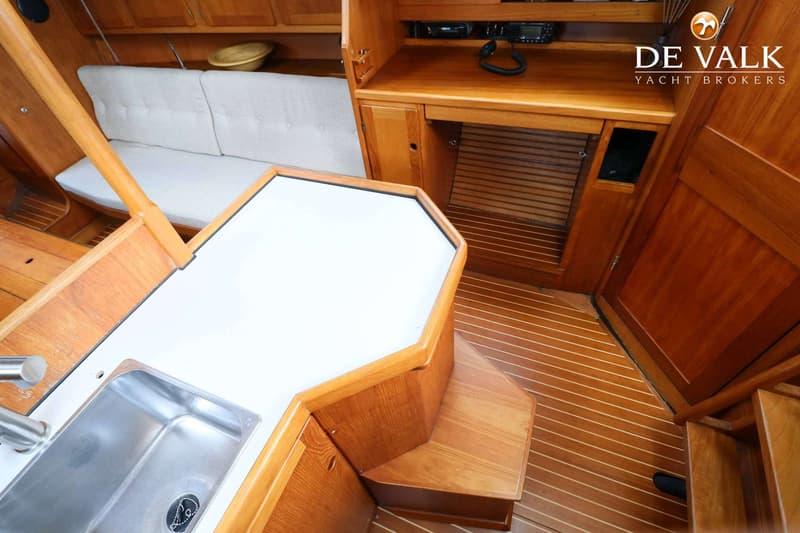 Een houten interieur met een aanrechtblad, spoelbak, bankje met kussens en een houten vloer.