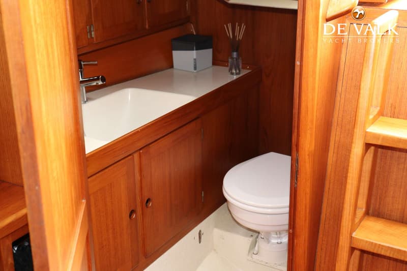 Een badkamer met een wastafel, kraan, toilet en houten kasten.