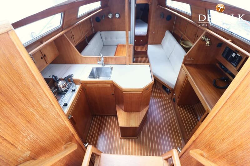 De foto toont het interieur van een boot met een kombuis, zithoeken en een doorgang naar een slaapcabine. — Faurby 396