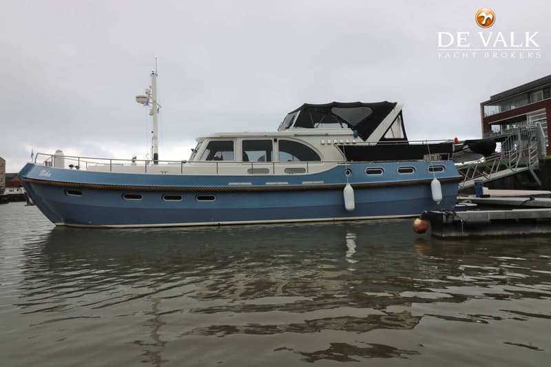 Een blauw-witte motorboot met de naam "Neba" ligt aan een steiger onder een bewolkte hemel. — Boarncruiser 50 Classic Line