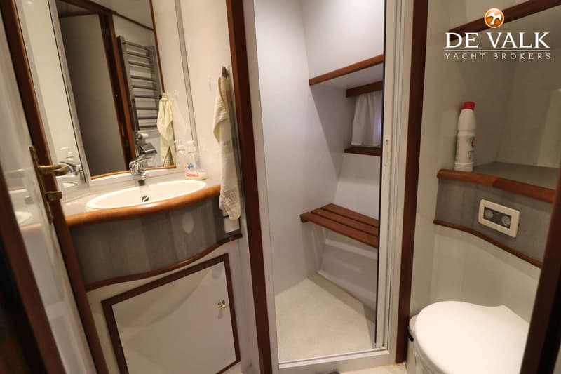 Een badkamer met een wastafel, spiegel, douchecabine en toilet.