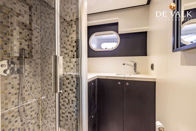 Een badkamer met een douchecabine met glazen deur, een wastafel met kraan en een spiegel aan de muur.