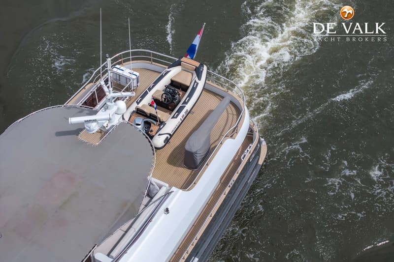 Een bovenaanzicht van de achterkant van een boot met een bijboot, een Nederlandse vlag en een Simrad radar.