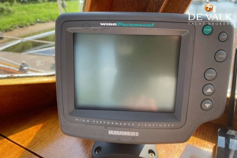 Een grijze Humminbird Wide Paramount fishfinder met knoppen en een scherm, gemonteerd op een houten oppervlak.