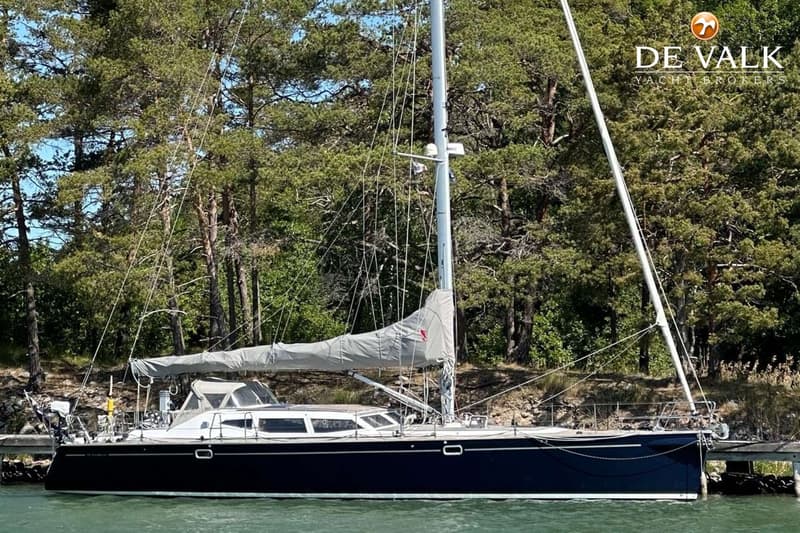 Een donkerblauwe zeilboot met een witte opbouw en opgerolde zeilen ligt aangemeerd aan een houten steiger. — Nordbaelt 50