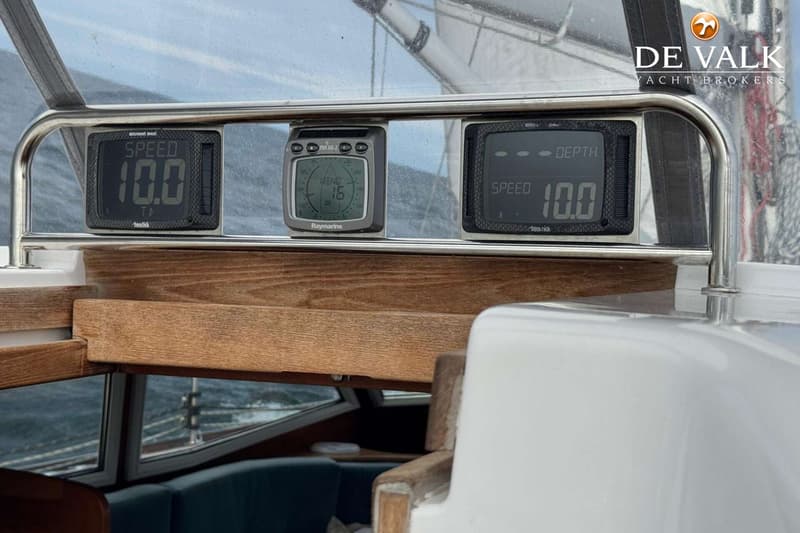Een donkerblauwe zeilboot met een teakdek en een witte opbouw ligt afgemeerd in een haven. — Nordbaelt 50