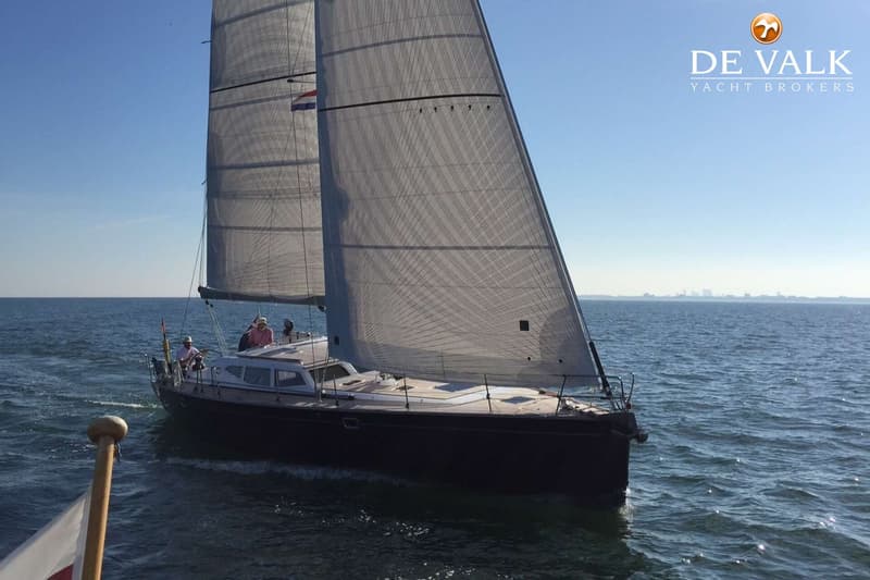Een zeilboot met een donkerblauwe romp en een teakhouten dek, met twee stuurwielen en de tekst "hordbaelt 50" op de spiegel.