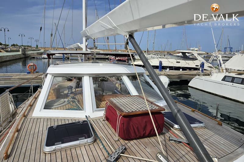 Een bovenaanzicht van het dek van een zeilboot met een kajuit, mast en giek, liggend in een haven. — Premier Dixon 62