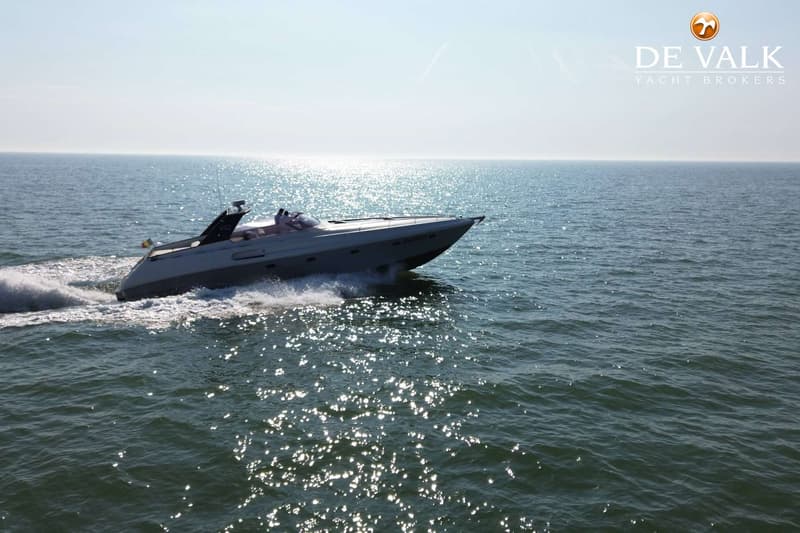 Een grijze motorboot vaart over het water, met een vlag aan de achterkant en opschrift "V52" en "B41833".