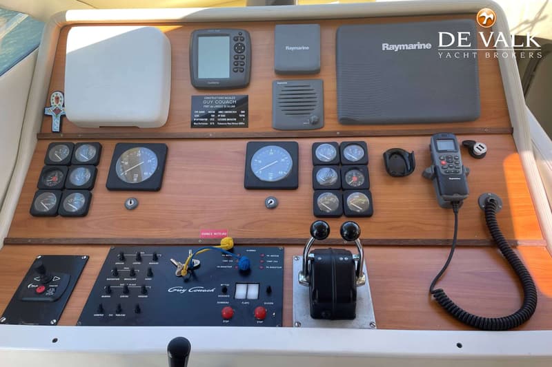 Een gedetailleerd overzicht van het dashboard van een boot met diverse meters, knoppen, een marifoon en navigatieapparatuur.