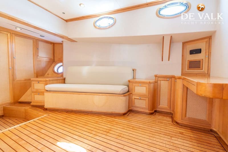 Een interieur van een boot met houten vloer, een beige bank, houten kasten en patrijspoorten. — Gullet 27