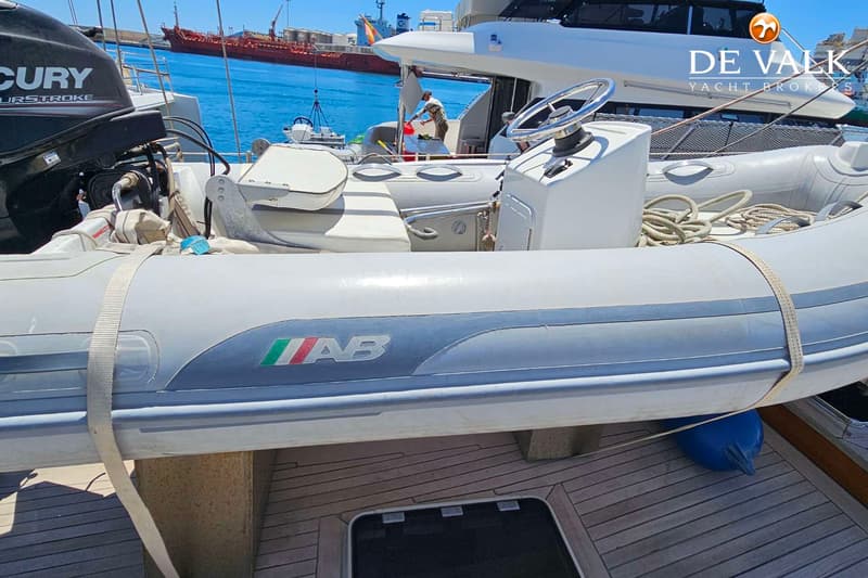 Een grijze rubberboot met "AB" en de Italiaanse vlag op de zijkant, vastgemaakt op een teakhouten dek.