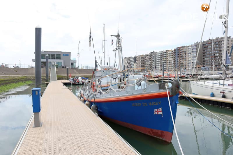 Een blauw-rood schip met de naam "JOZEF DE WAEY" ligt afgemeerd aan een steiger in een haven. — Waarschip 1076 Custom