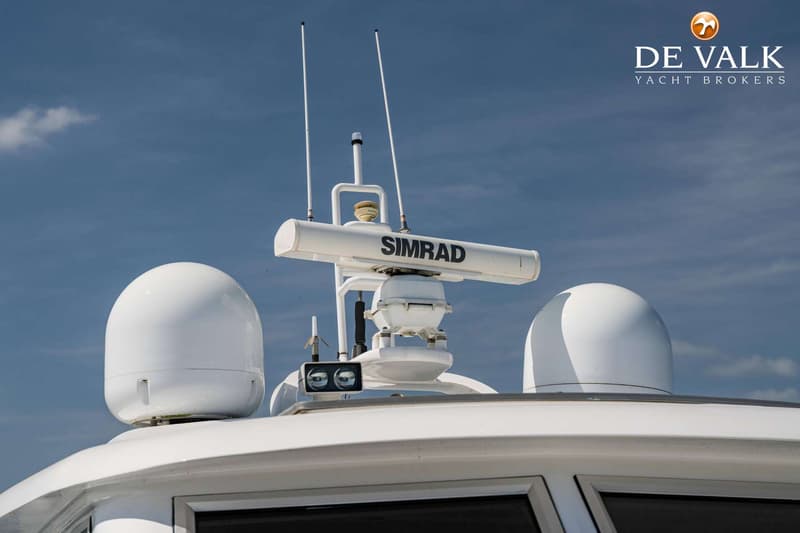 Een witte radar van het merk Simrad, twee witte antennes en twee witte koepels zijn zichtbaar op het dak van een boot.