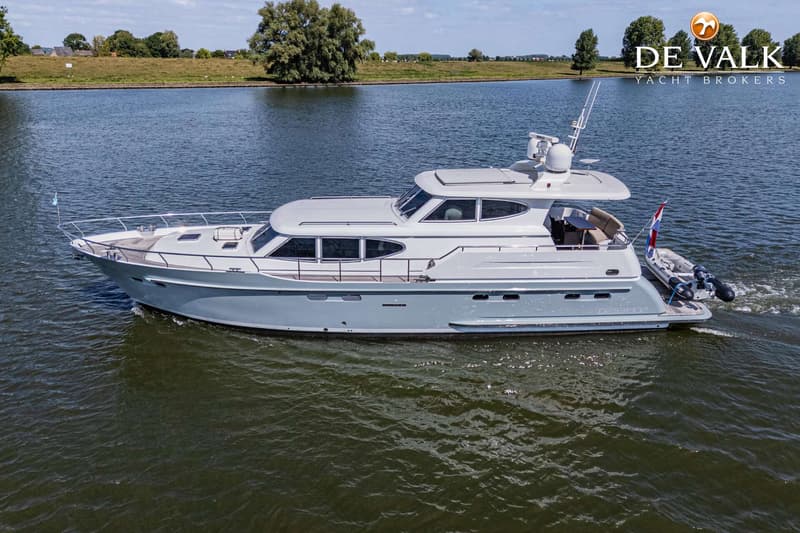 Een grijze motorboot vaart op een waterweg met een groene oever en bomen op de achtergrond. — Vripack 63 Custom M/Y