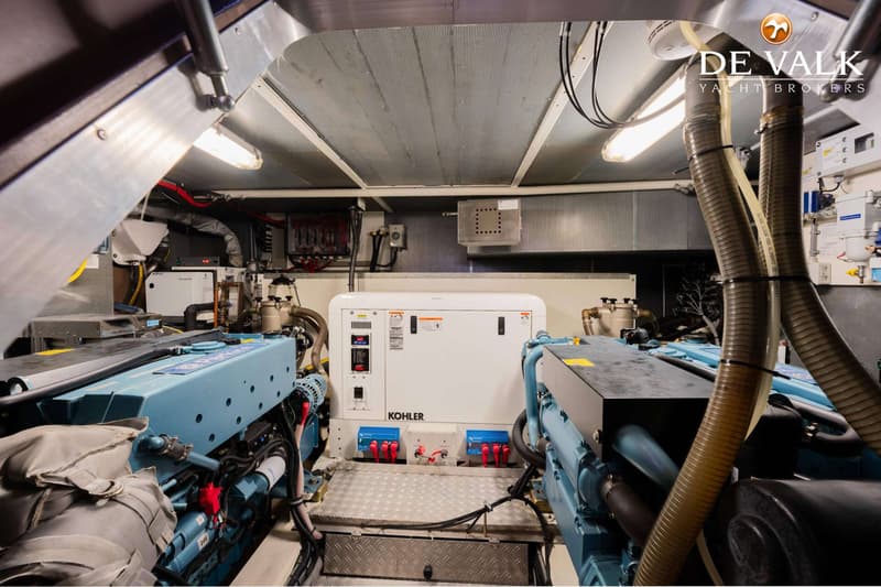 Een machinekamer met twee blauwe motoren en een witte Kohler generator in het midden.