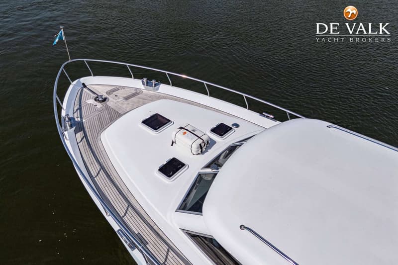 Een bovenaanzicht van de boeg van een witte motorboot met een teakhouten dek en een reddingsvlot. — Vripack 63 Custom M/Y