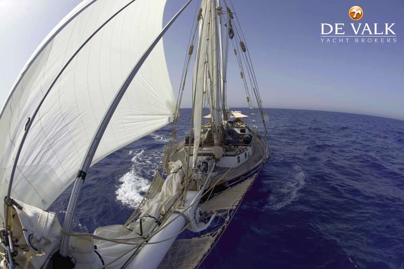 Een zeilboot met twee masten en witte zeilen vaart op open water onder een helderblauwe lucht. — Schooner Sitting Bull 19.80