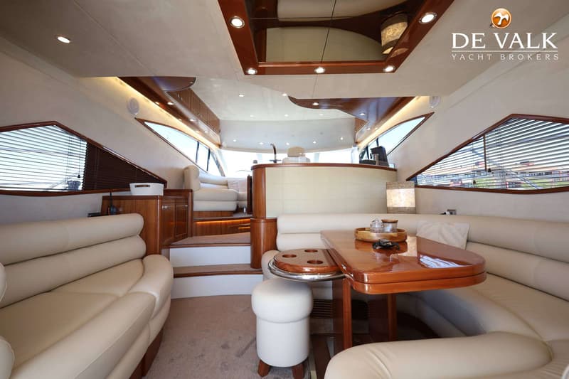 De foto toont het interieur van een boot met een zithoek, een tafel en een trap. — Galeon 530 Fly